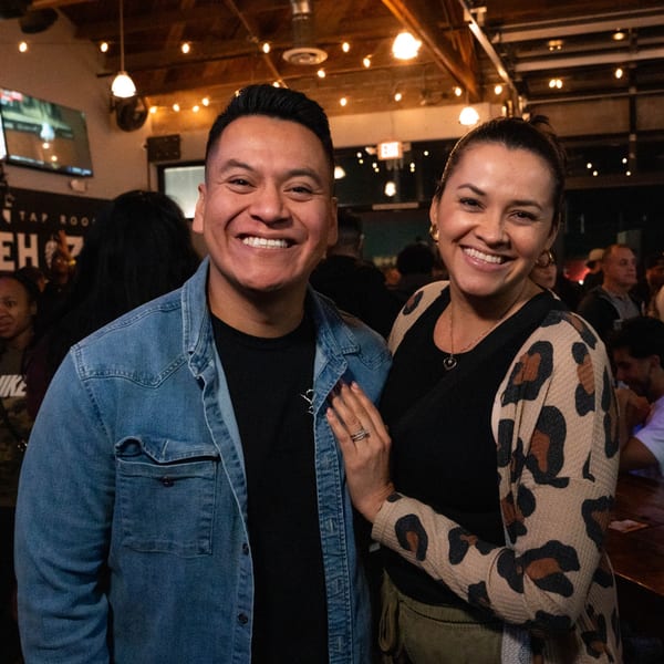 Smiling man in denim shirt and woman in leopard print cardigan at Servehzah Bottle Shop & Tap Room.