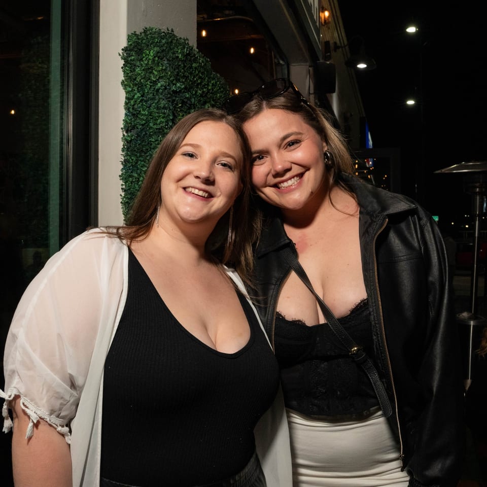 Two smiling women pose closely together at Servehzah Bottle Shop & Tap Room.
