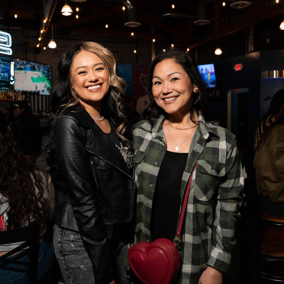 Two smiling women pose for a photo inside Servehzah Bottle Shop & Tap Room.