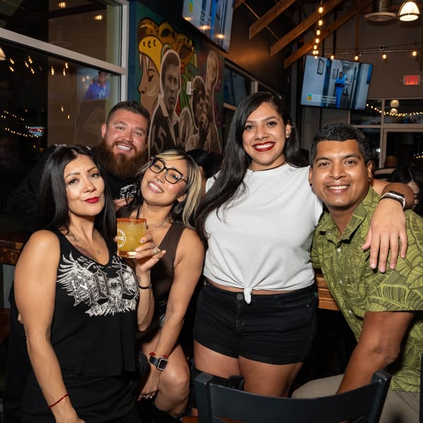 Five smiling friends, three women and two men, pose together at Servehzah Bottle Shop & Tap Room.