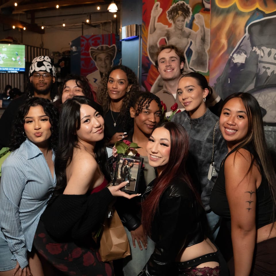 A group of diverse young adults smiling and posing for a photo inside Servehzah Bottle Shop & Tap Room.