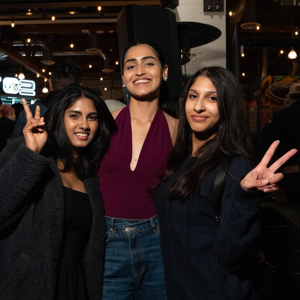 Three smiling women posing with peace signs at Servehzah Bottle Shop & Tap Room.