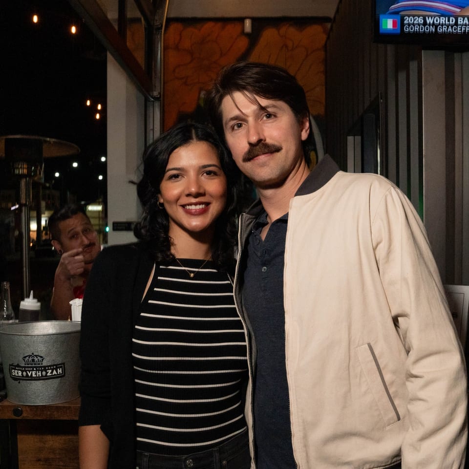A smiling couple poses for a photo at Servehzah Bottle Shop & Tap Room.
