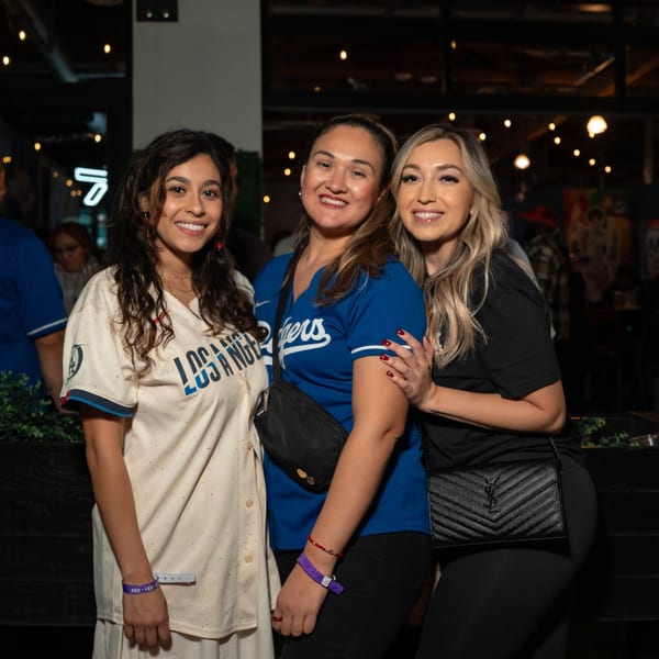 Three smiling women in Dodgers jerseys and casual attire pose together at Servehzah Bottle Shop & Tap Room.